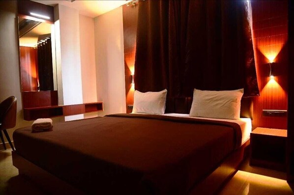 A hotel room with a large bed, a desk, and a chair.