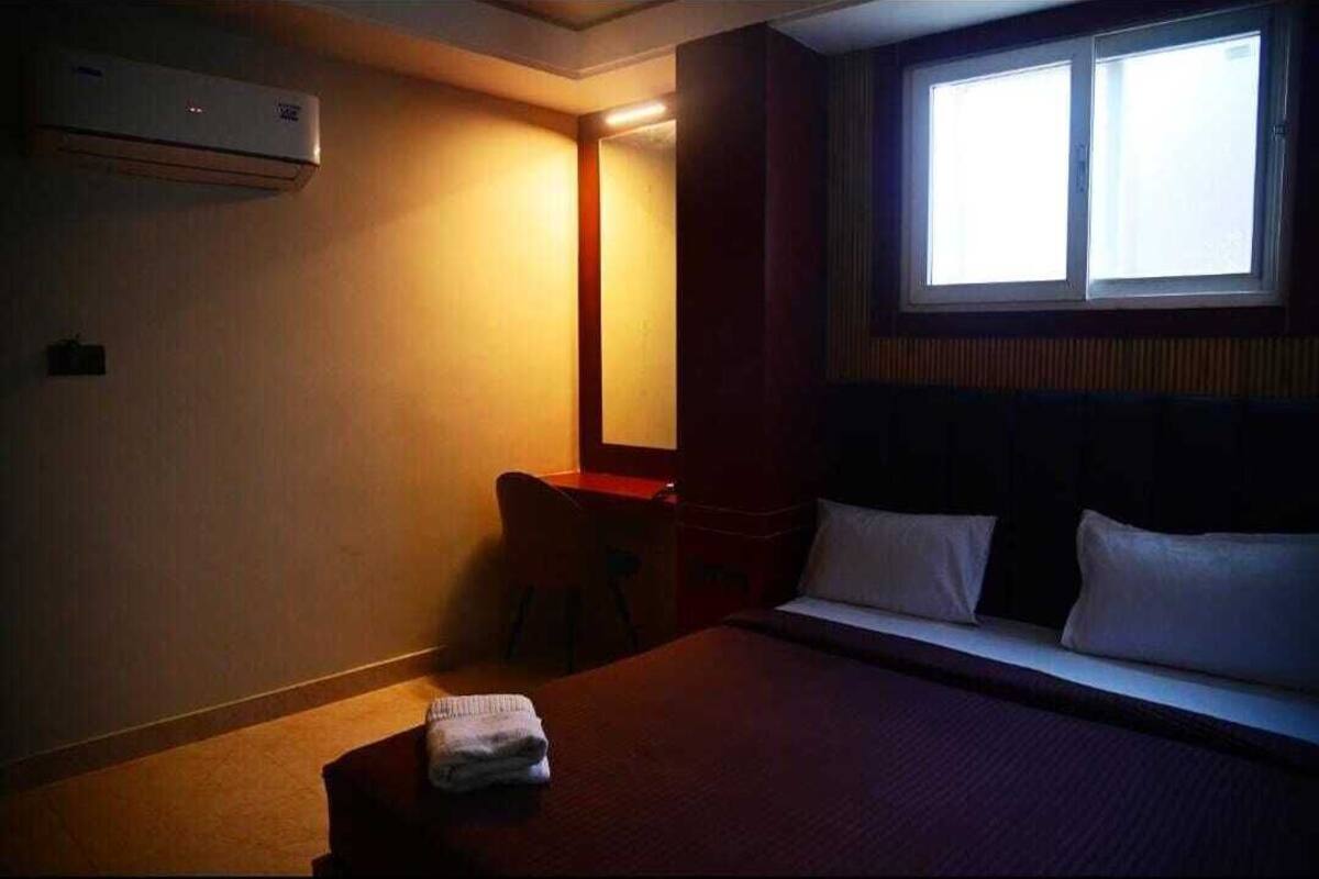 A hotel room with a bed, a desk, and a window.