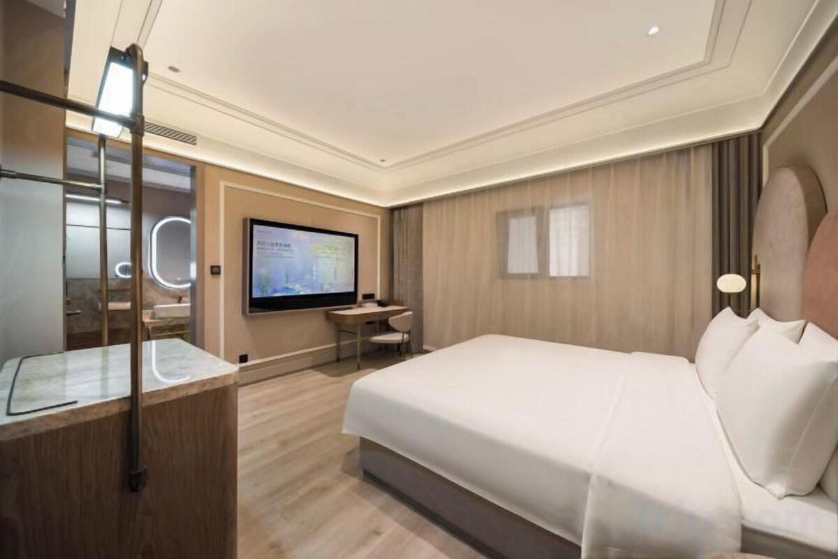Une chambre d’hôtel avec un grand lit, un bureau, une télévision et un miroir.