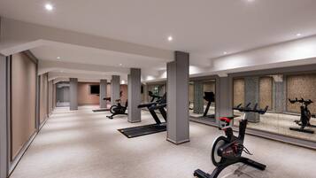 A modern gym with multiple exercise machines, a long corridor, and a mirrored wall.