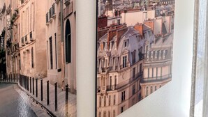 Two framed cityscape photographs, one depicting a narrow street with buildings and the other showing a view of the Eiffel Tower.