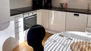A modern kitchen with white cabinets, a black countertop, and a dining area with a round table.