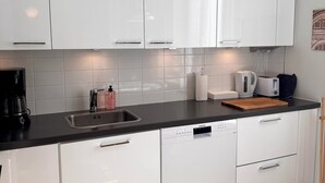 A modern kitchen with white cabinets, a black countertop, and a Siemens dishwasher.
