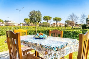 An outdoor dining area with a table set for two, surrounded by wooden chairs. - Renovated Holiday Home With Pool in Bibione (San Michele al Tagliamento)