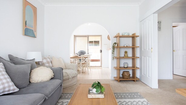 Una sala de estar con un sofá gris, una mesa de centro de madera y una alfombra estampada.
