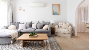 Una sala de estar con un sofá seccional gris, una mesa de centro de madera y un sillón color beige.