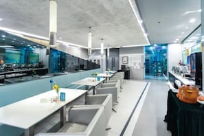 Un restaurante moderno con una barra alargada, varias zonas de estar y vistas a la cocina.