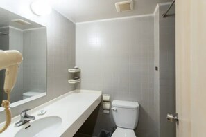 Un baño con lavamanos, espejo y retrete blancos.