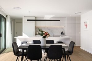 Cocina moderna con armarios blancos, protector contra salpicaduras de mármol y una isla central con un florero.