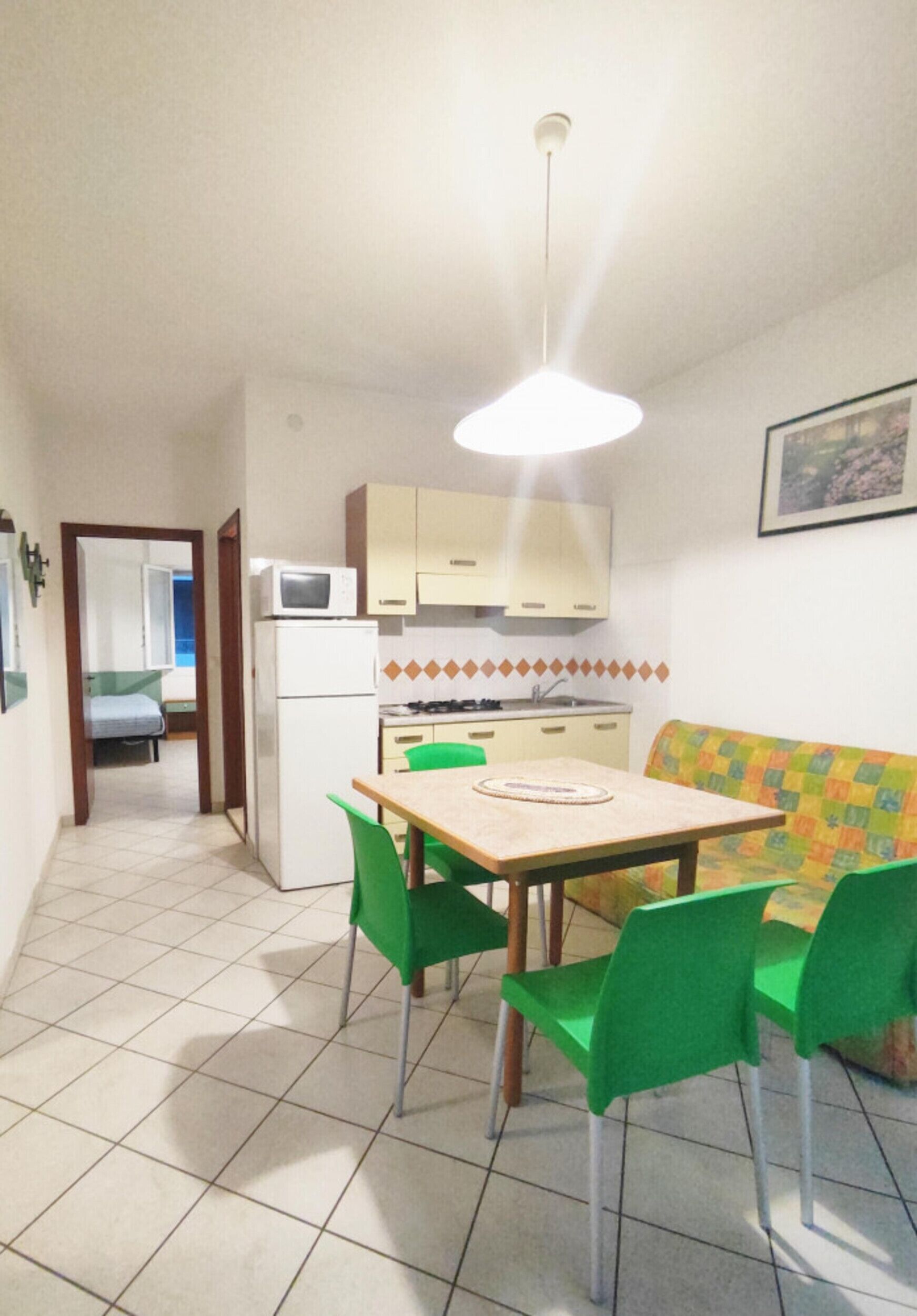 A compact kitchen with a microwave, refrigerator, and a dining area with a table and chairs.