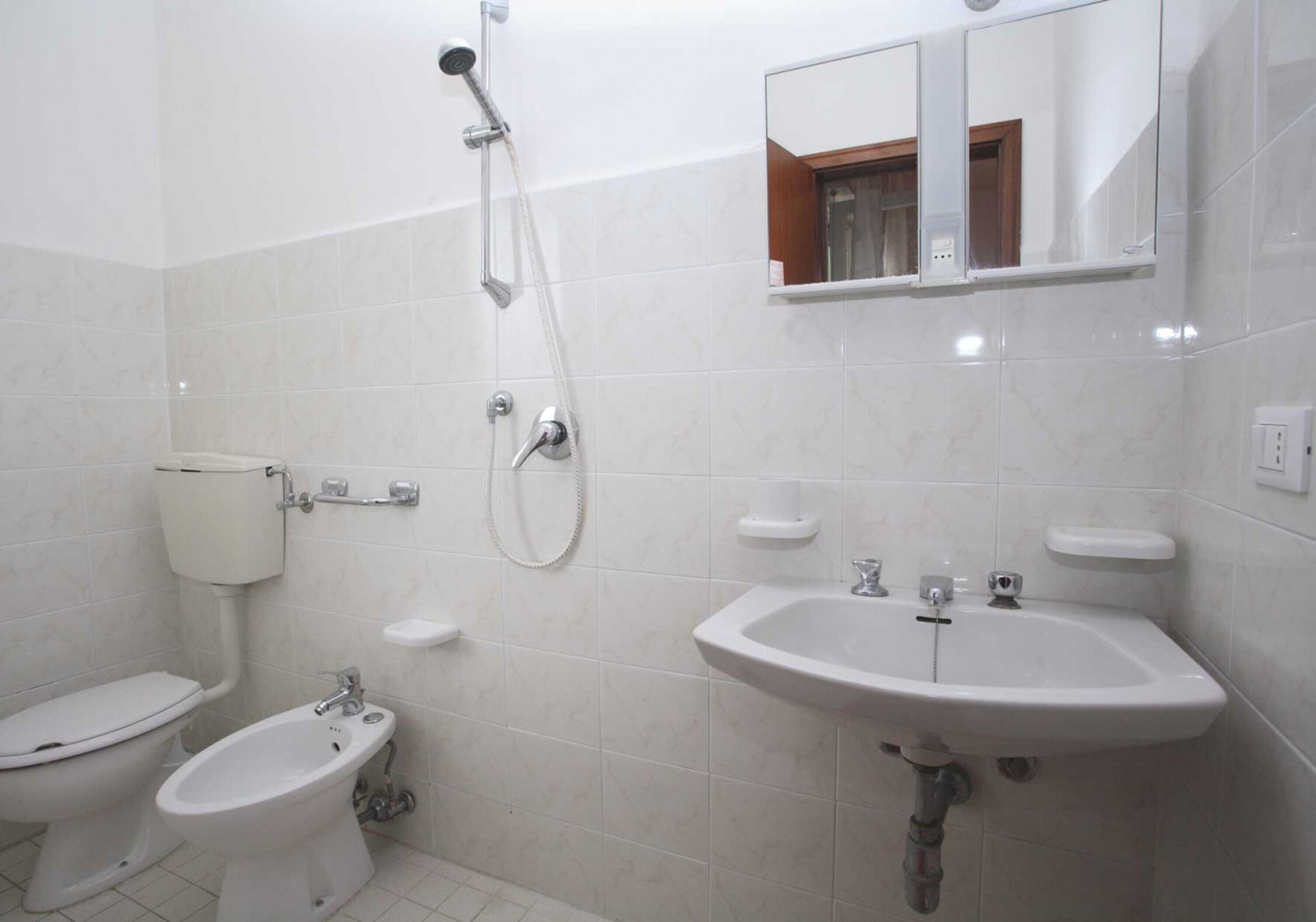 Ein Badezimmer mit Toilette, Bidet, Waschbecken und einem Spiegel darüber.