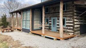 A rustic log cabin with a porch, a wooden bench, and a small table. - Red Fox Ridge Cabin Retreat - No Cleaning Fee. Relax and unwind (Butler)