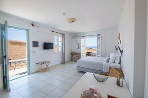 A bedroom with a bed, a TV, a window, and a view of the outdoors.