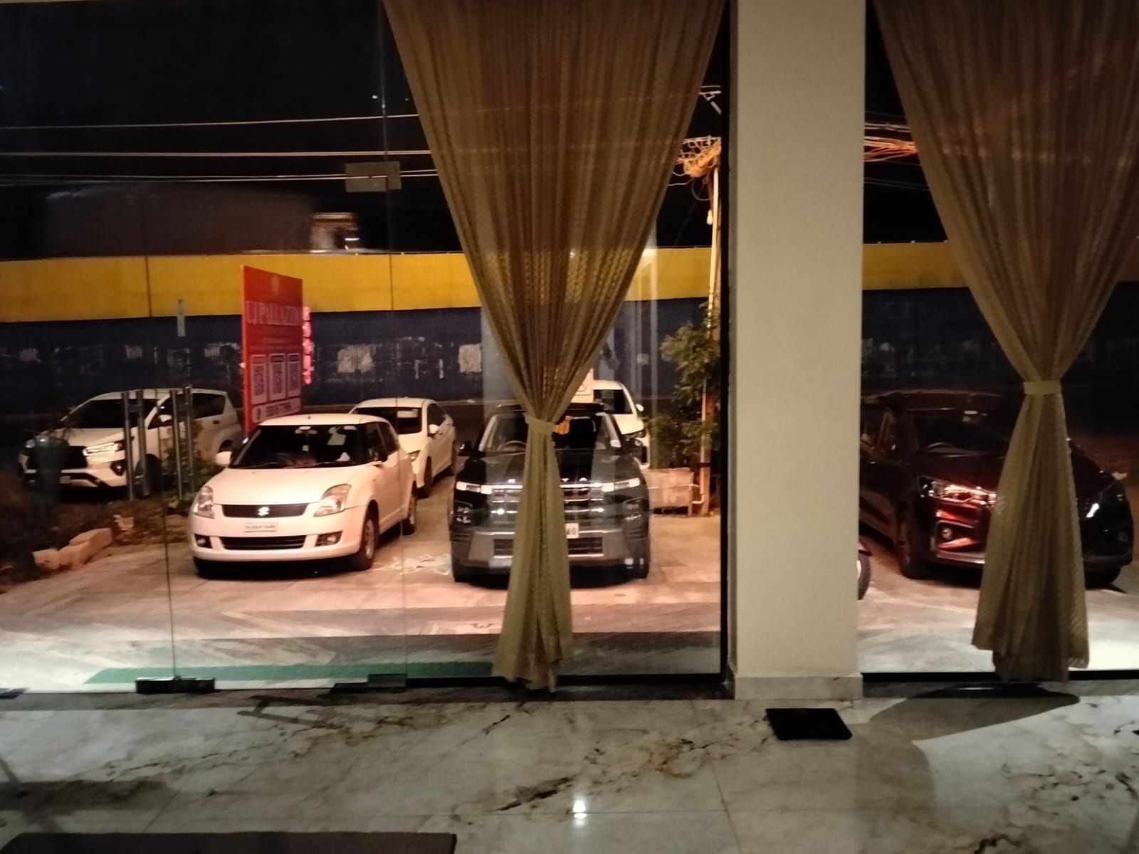 A parking area with multiple cars parked in front of a building with yellow and blue walls.