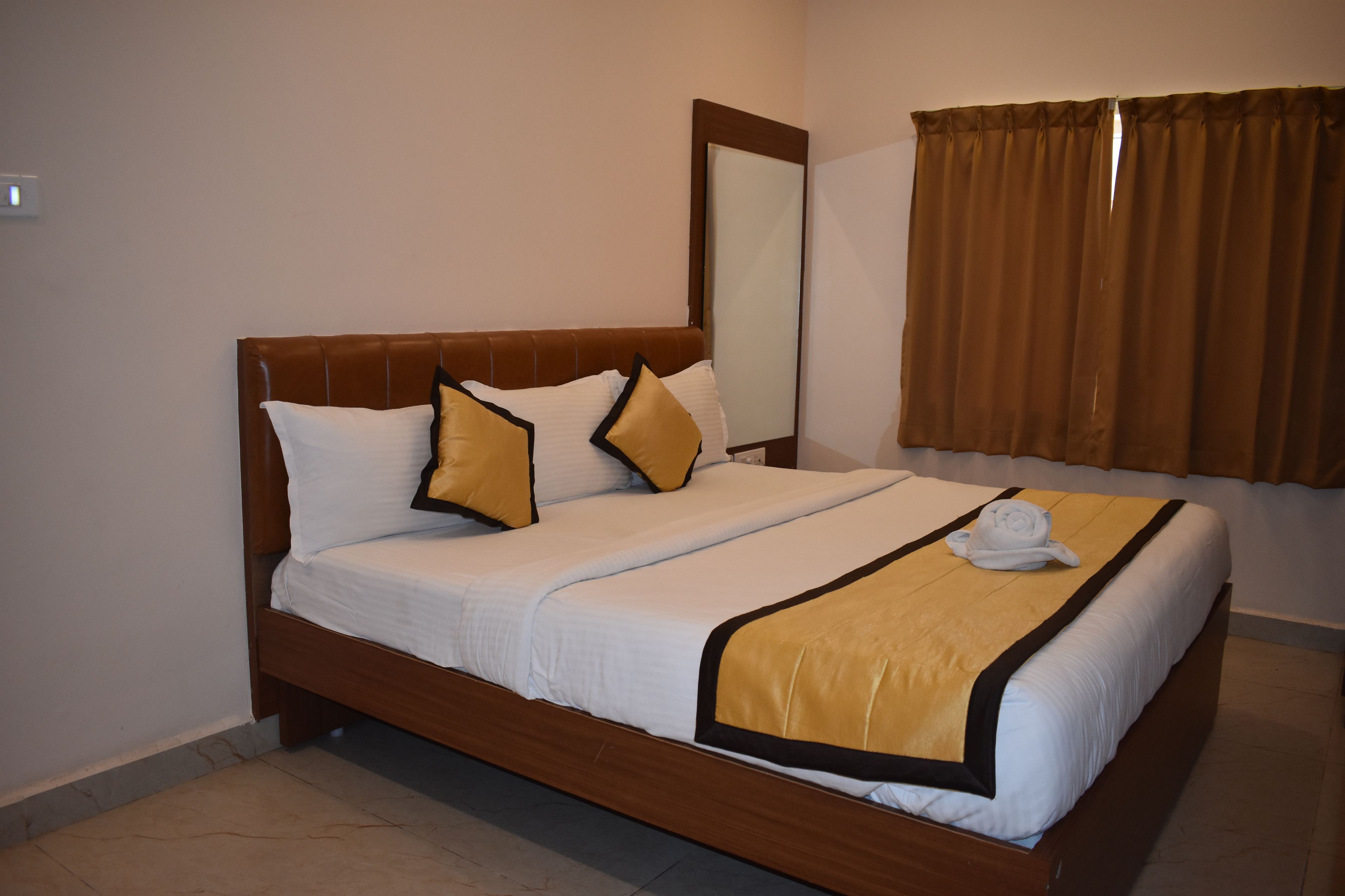Una habitación de hotel con una cama grande, un espejo y una ventana con cortinas.