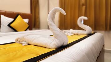 A hotel room with a neatly made bed featuring a unique swan-shaped towel arrangement.