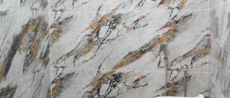 A bathroom with marble walls and a modern toilet.