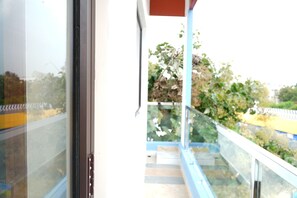 A view from a balcony with a glass door, a blue railing, and a staircase leading outside. - UJ PALLAZZIO - Business Class Luxury Hotel (Tiruvannamalai)