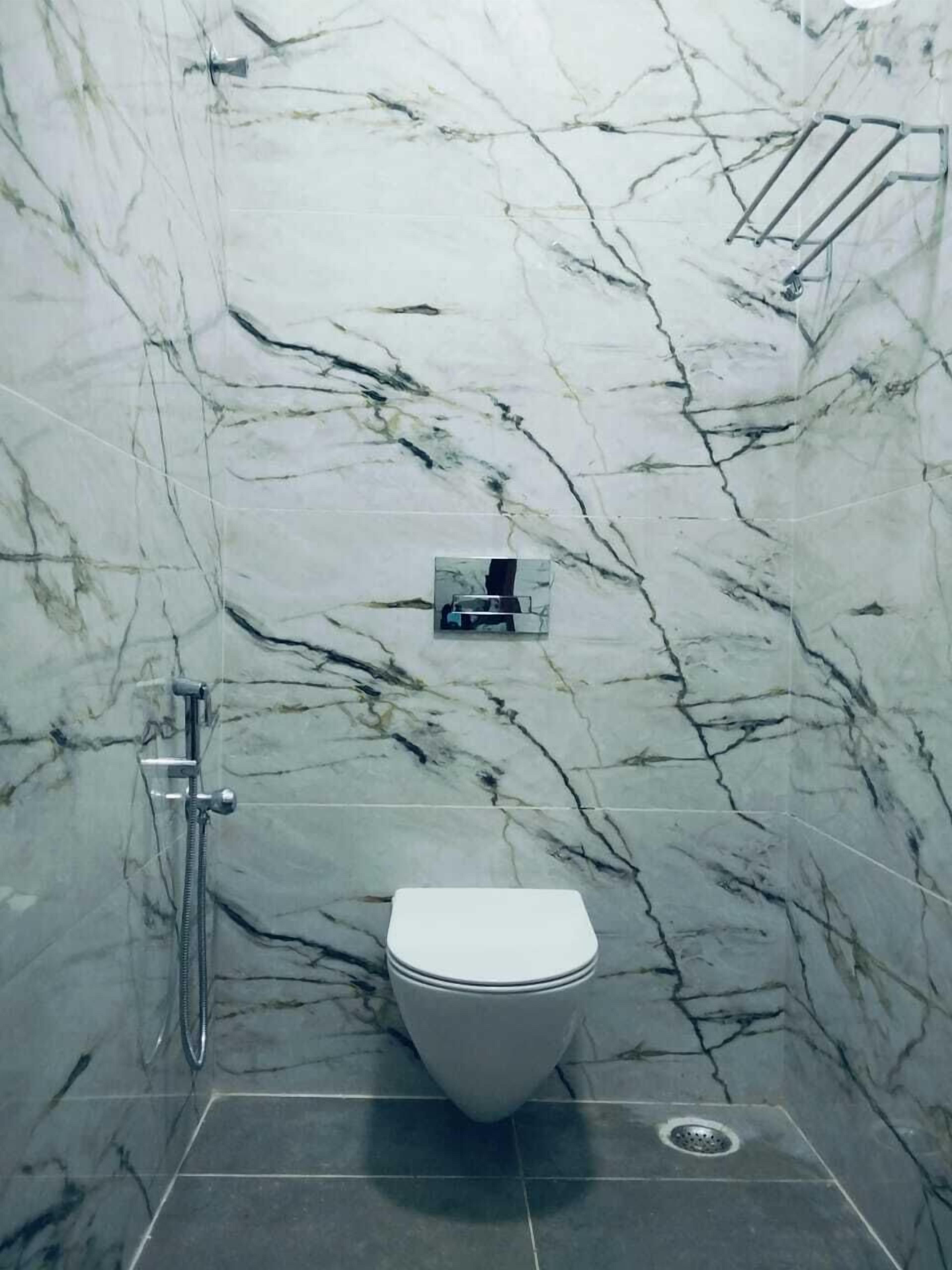 A bathroom with a toilet, a shower, and a towel rack.