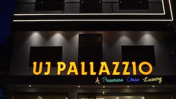 A multi-story building with illuminated signage reading 'UJ PALLAZZO A Business Class Luxury.'