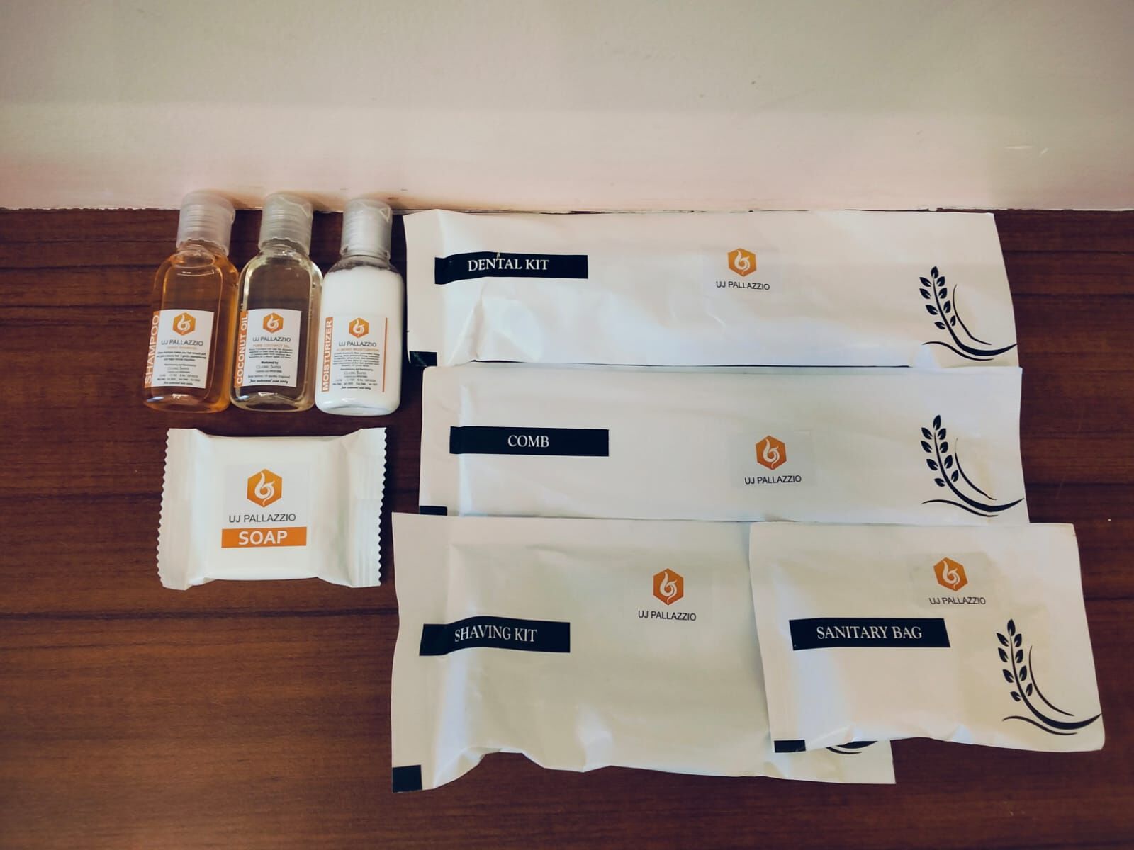 A dental kit, shaving kit, sanitary bag, comb, and soap arranged on a wooden surface.