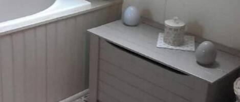 Un baño con tragaluz, bañera, inodoro y tocador con cajones.