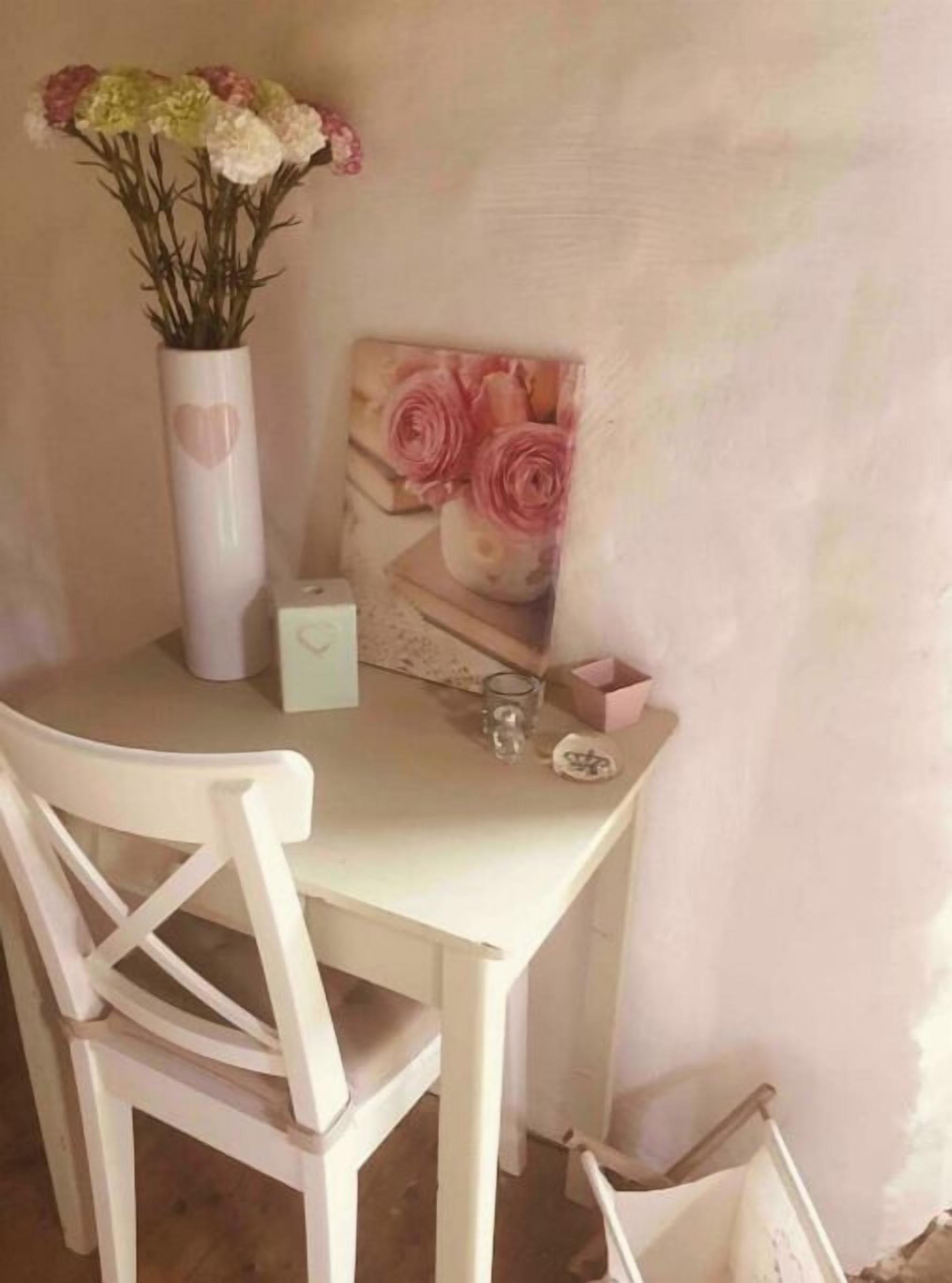 Una mesa blanca con un florero, un vaso y una pequeña caja.