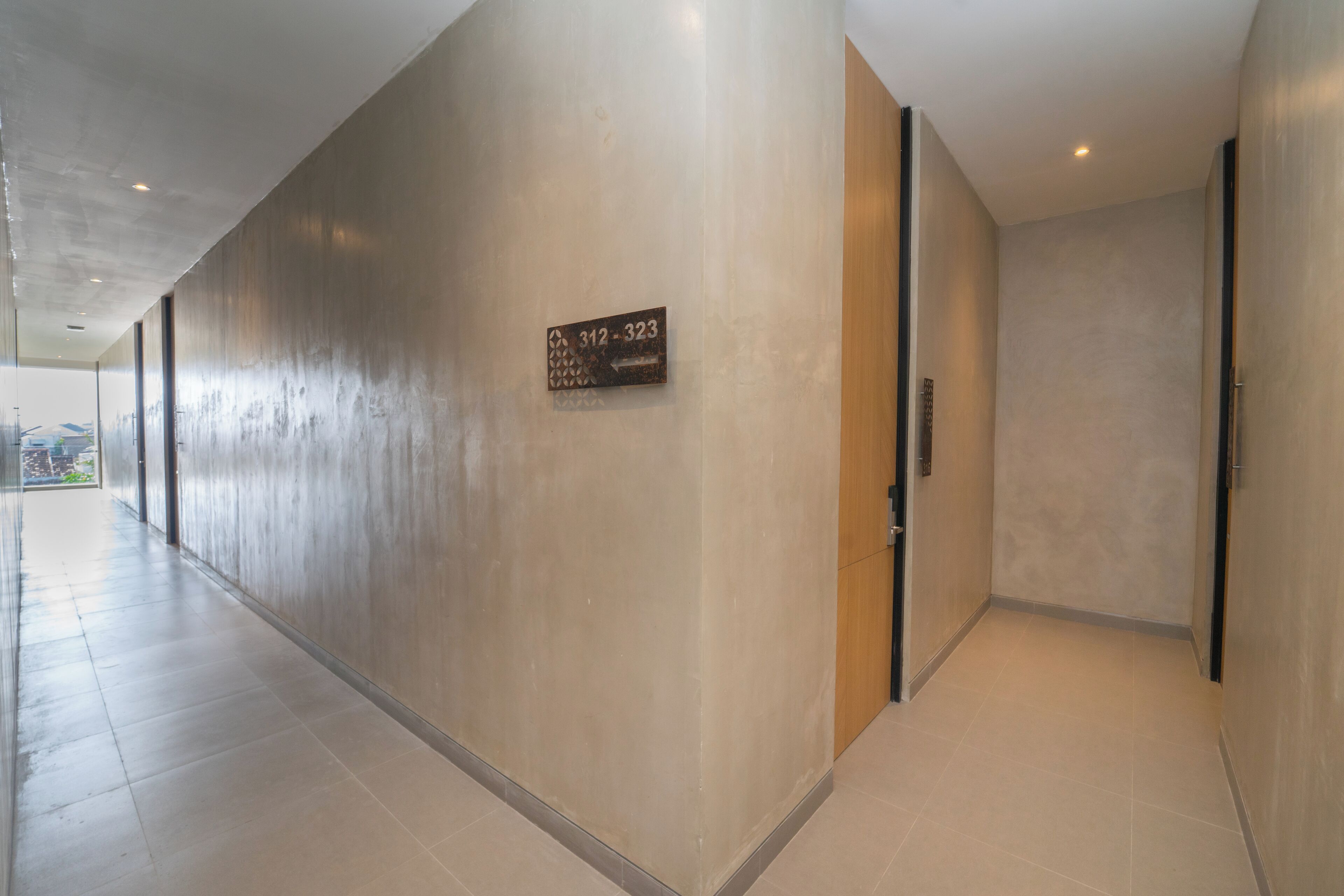 A hallway with a contact number sign, a door, and a tiled floor.
