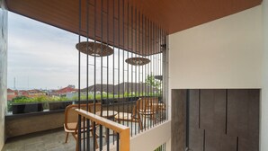 A balcony with a wooden railing, wicker chairs, and a table. - Keenan Living Luxe Seturan (Depok)