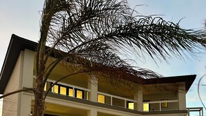 A multi-story building with balconies, a swimming pool, and a palm tree in the foreground. - Luxury Oceanfront Oasis, Private Pool, Steps to Beach (Port Aransas)