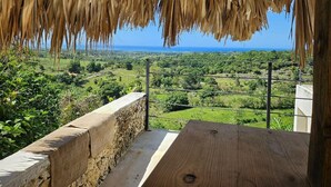 Una mesa de madera bajo un techo de paja, con vistas a un exuberante paisaje verde y una vista despejada del mar.