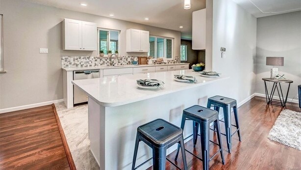 Una cocina moderna con armarios blancos, una isla grande con taburetes e iluminación colgante.