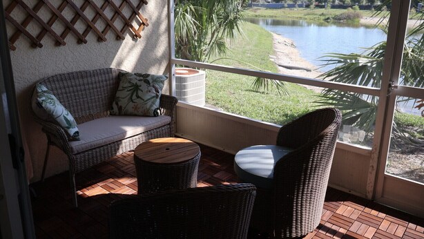 A balcony with wicker furniture, a view of a lake, and a lattice wall. - Charming 2-bedroom townhome with water view and resort style pool (Bradenton)