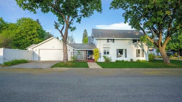 A two-story house with a garage, a covered porch, and a well-maintained lawn.