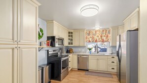 Una cocina con armarios de colores claros, electrodomésticos de acero inoxidable y suelo de madera.