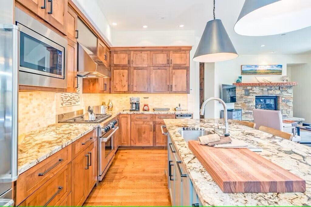 Une cuisine moderne avec des meubles en bois, un grand îlot central et une cheminée en pierre.