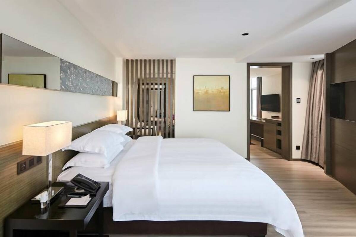 Una habitación de hotel con cama, mesita de noche, lámpara y televisión.