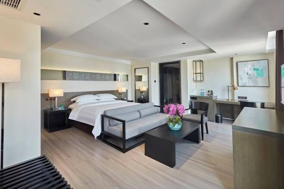 Una habitación de hotel moderna con una cama, un sofá, un escritorio y una mesita de centro.