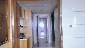 A hallway with a wooden cabinet, a metal kettle, and a tiled wall. - Anqing Tianyi Hotel (Anqing)