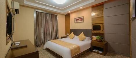 A hotel room with a large bed, a desk, a television, a mirror, and a window with curtains.