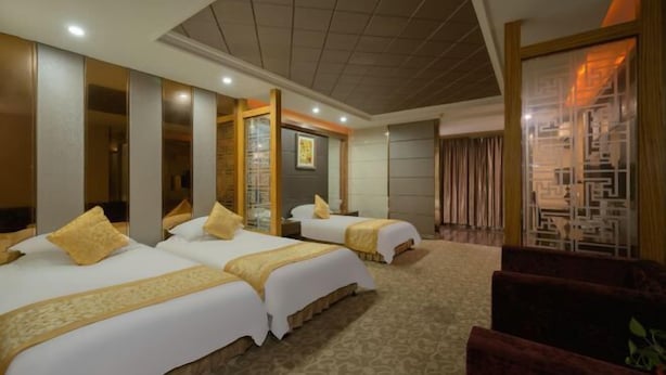 A hotel room with two beds, a large mirror, and a seating area with a red chair. - Anqing Tianyi Hotel (Anqing)