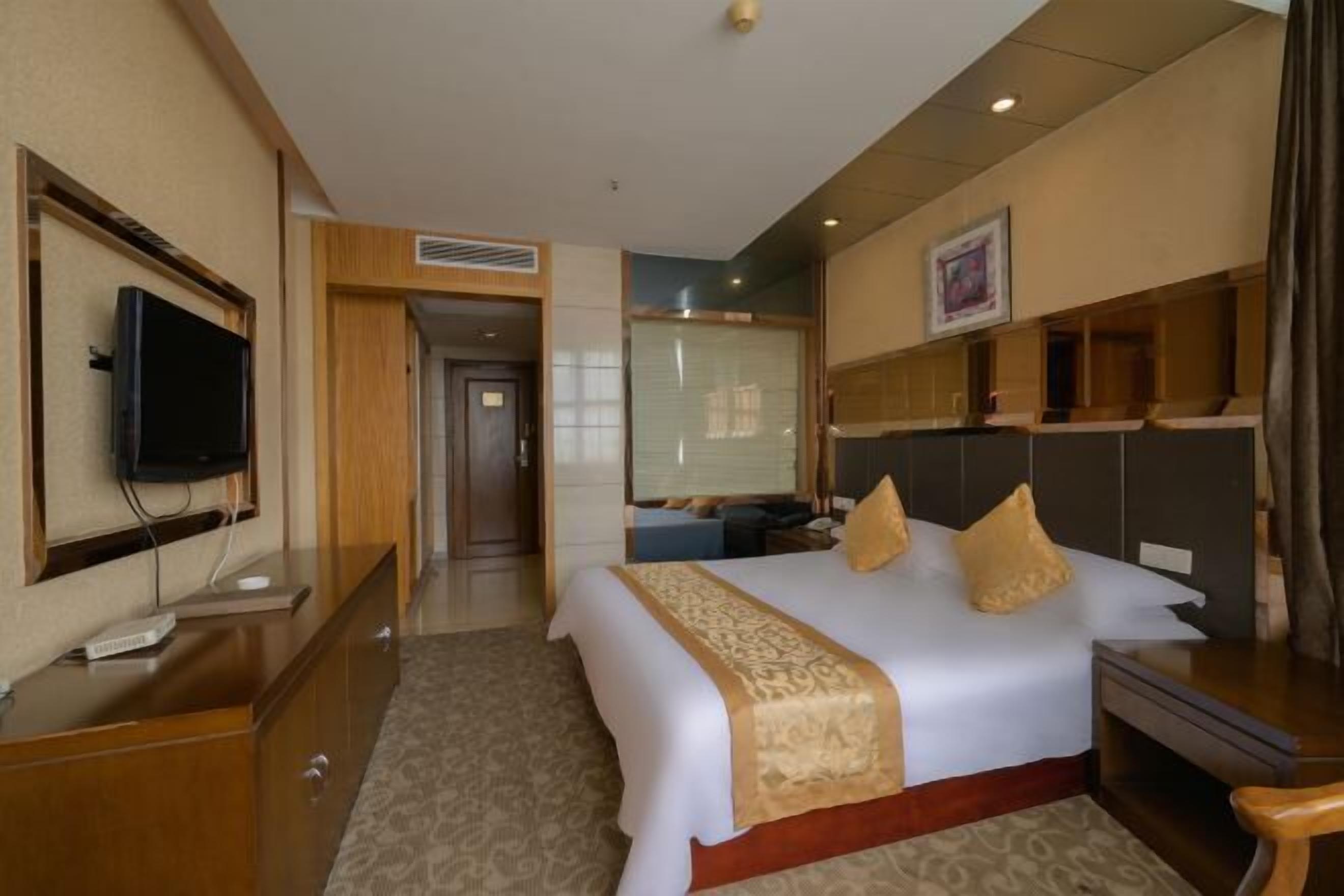 Une chambre d’hôtel équipée d’un lit, d’une télévision, d’un bureau et d’un miroir.
