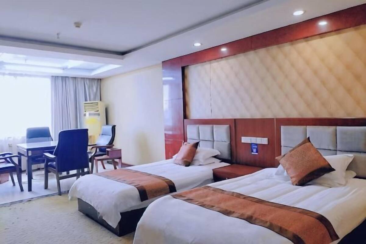A hotel room with two beds, a desk, and a chair.