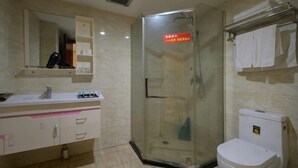 A bathroom with a glass-enclosed shower, a white toilet, and a vanity with a mirror and storage. - Anqing Tianyi Hotel (Anqing)