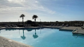 A swimming pool with lounge chairs and palm trees.