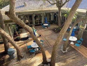 An outdoor patio area with wooden flooring, blue chairs, and umbrellas. - Beautiful One Bedroom Retreat (Horry County)