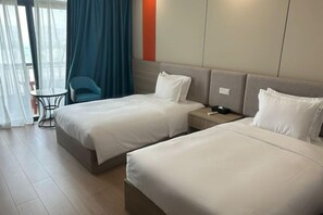 A hotel room with two beds, a small table, a chair, and a view of the outdoors. - Xiamen Jingbang Hotel (Xiamen)