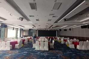 A conference room with rows of white chairs, a stage, and a large screen. - Xiamen Jingbang Hotel (Xiamen)