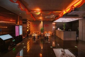 A lobby with a reception desk, seating area, and a digital information board. - Xiamen Jingbang Hotel (Xiamen)