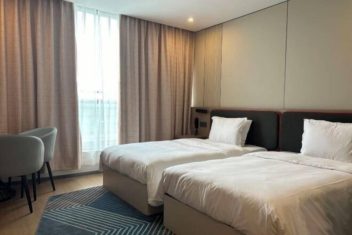 Ein Hotelzimmer mit zwei Betten, einem Schreibtisch und Blick ins Freie.